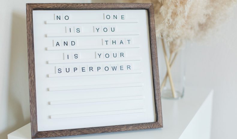 Tabliczka z drewnianą ramką; na niej cytat: „No one is you and that is your superpower”.
